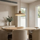 Kaia natural stone and oak pendant light illuminating a modern dining room.