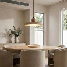 Kaia natural stone and oak pendant light illuminating a modern dining room.