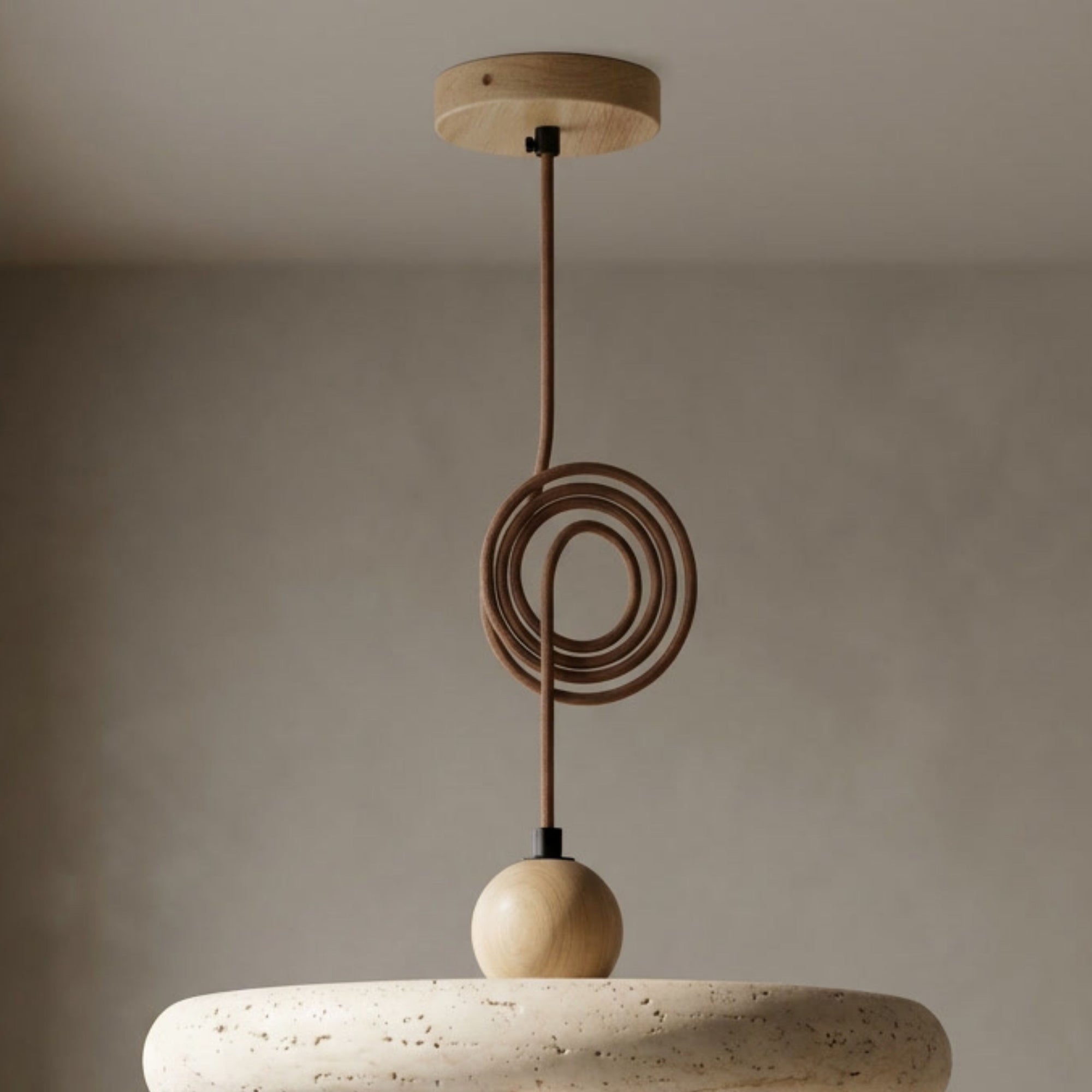 Kaia natural stone pendant light with a circular textured stone shade, oak arm, and coiled brown cord.