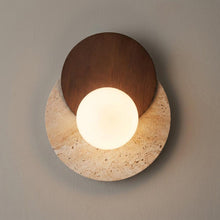 Lyra wall sconce with a glowing opal glass orb on a round natural stone base and dark walnut detail.