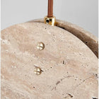 Close-up of a Nacre Travertine Pendant Light, showing its natural stone texture, brass hardware, and brown braided cord.