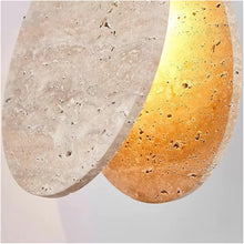 Close-up of a Nacre Travertine Pendant Light, showcasing its textured, hand-shaped stone and warm glow.