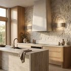 Two Pulse Travertine Up/Down Wall Lights illuminate a stone wall in a modern kitchen.